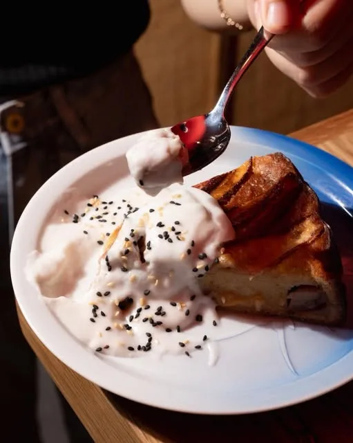 A slice of bánh chuối nướng with coconut cream and black sesame
