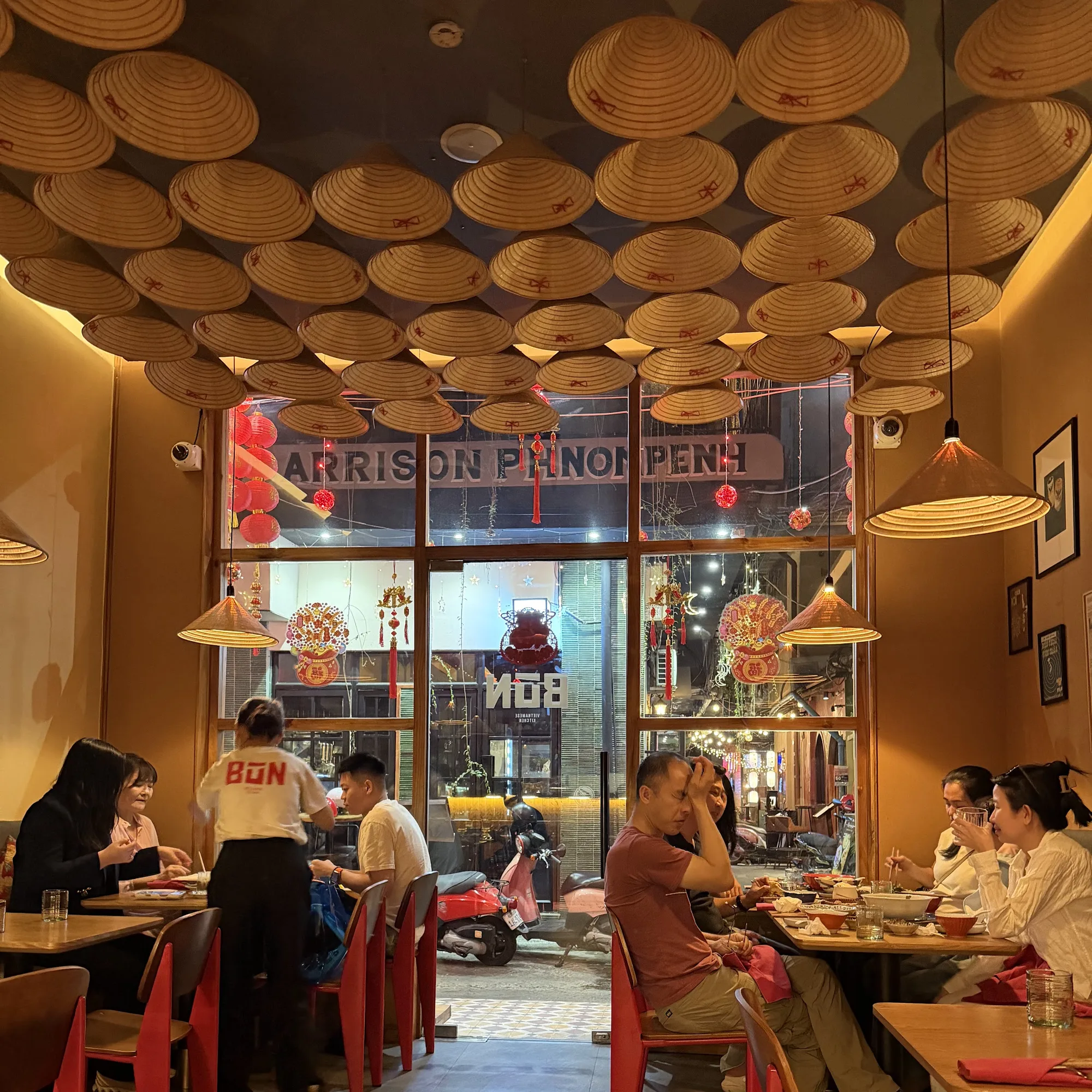 Guests eating at red tables, seen from the open shopfront